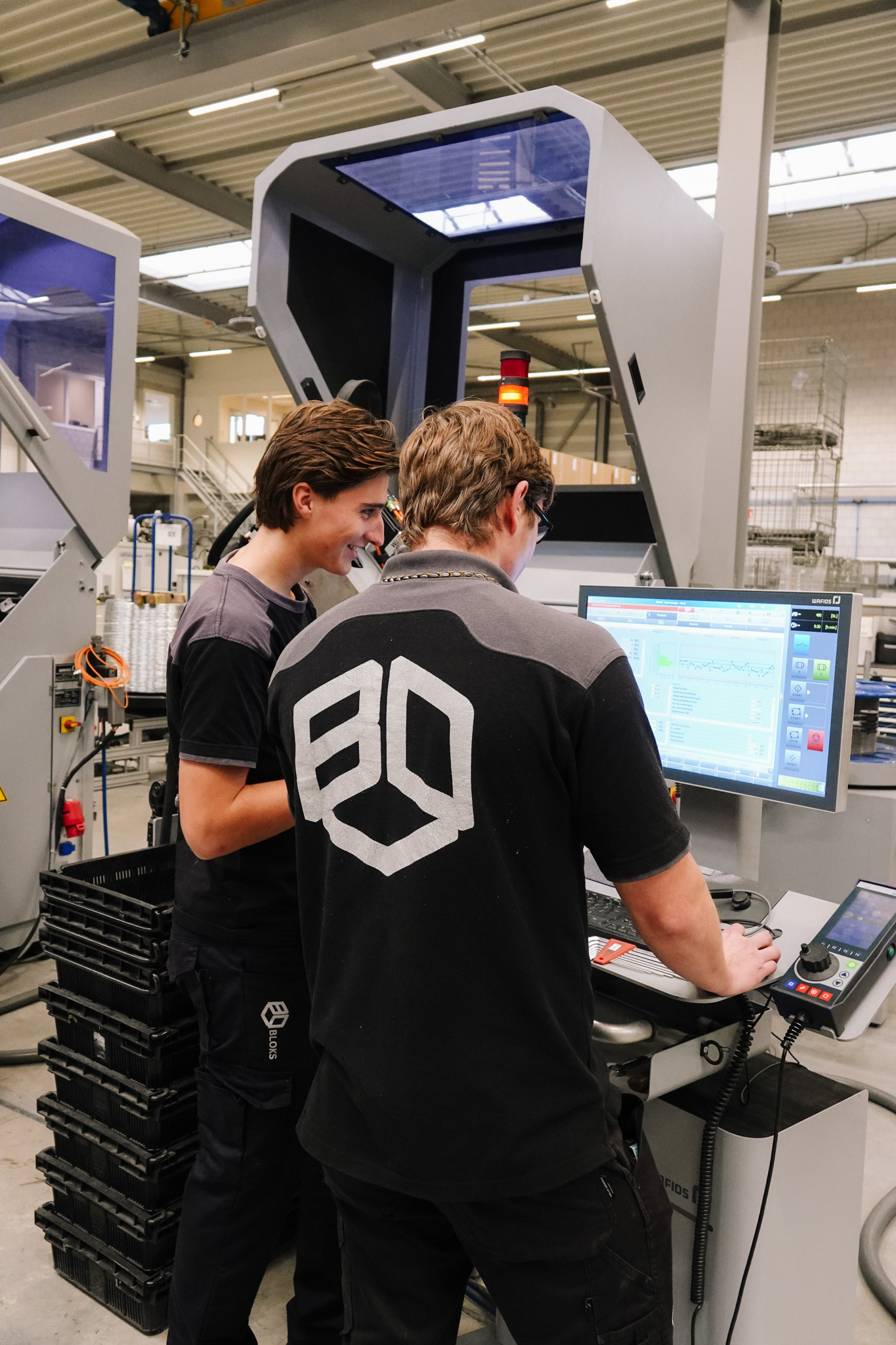 Twee collega's aan het werk bij een machine in de fabriek